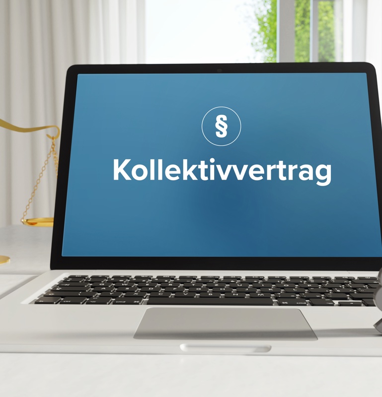 Laptop im Büro mit Begriff Kollektivvertrag auf dem Monitor - daneben  Paragraf und Waage