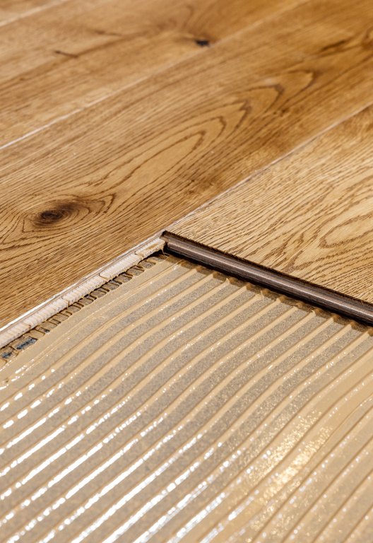 Parkett wird mit Baukleber verlegt